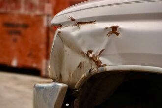 the front end of a white car with rust on it