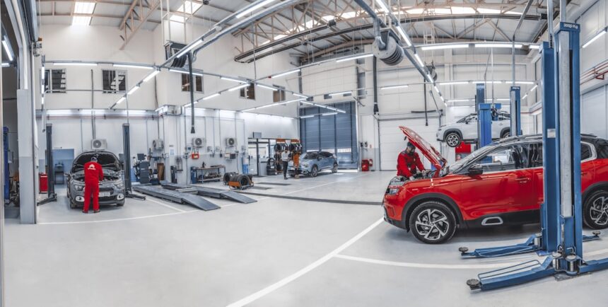 Mechanics working on cars in a bright, spacious automotive repair workshop