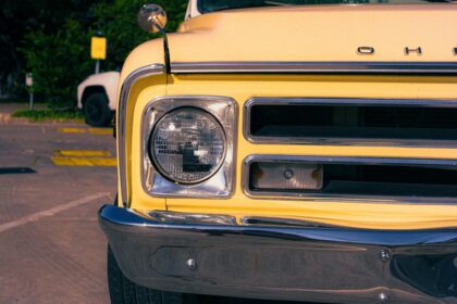 Yellow vintage truck's headlight, grille, and bumper