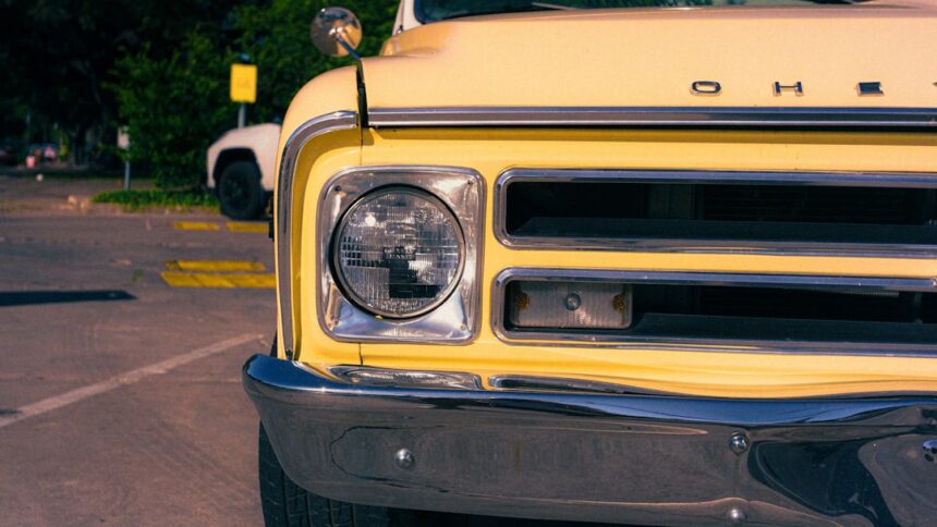 Yellow vintage truck's headlight, grille, and bumper