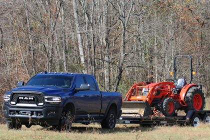 a blue pickup truck towing a red tractor