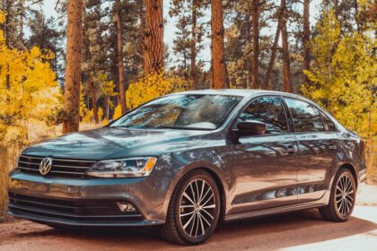 a silver car parked in front of a forest