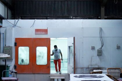 woman in gray hoodie standing in front of white red and blue door