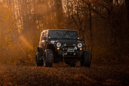 A black jeep wrangler drives on a dirt road