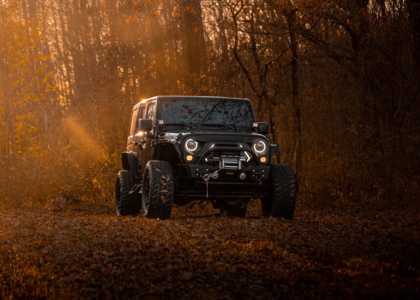 A black jeep wrangler drives on a dirt road