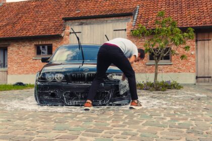 A person washing a black car with soap suds