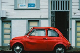 red Volkswagen Beetle car parked in front of white house