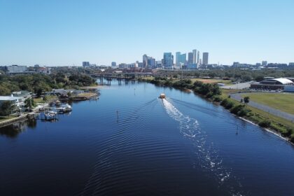 white boat on body of water near city buildings during daytime
