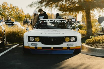 White vintage car with racing stripes and people