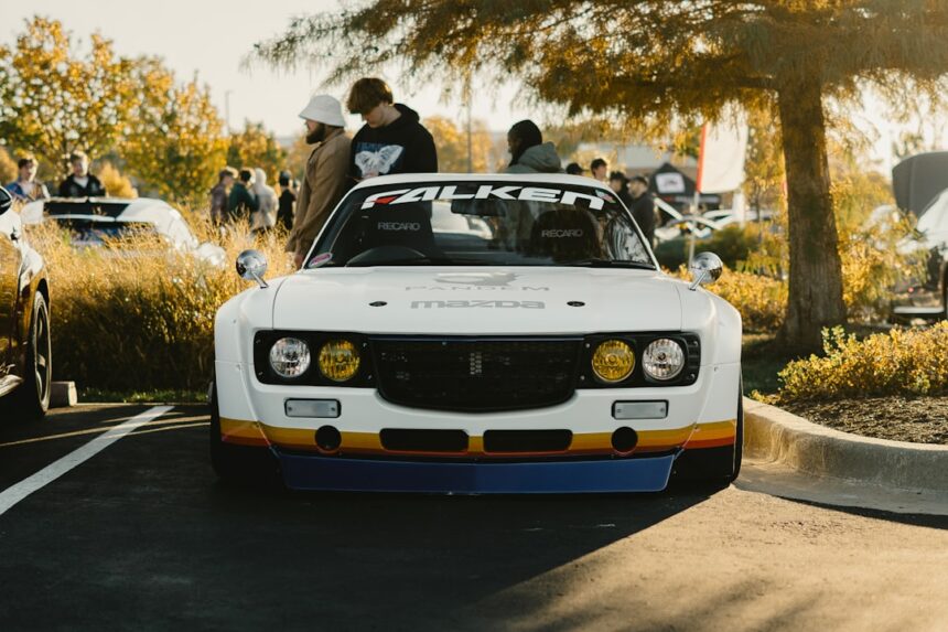 White vintage car with racing stripes and people
