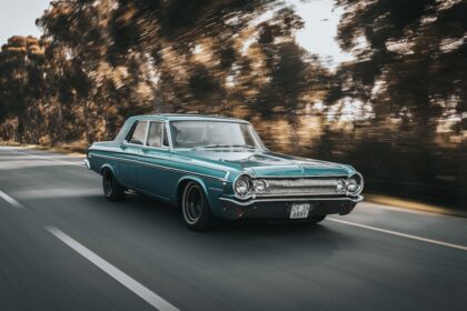 teal sedan on roadway beside the trees