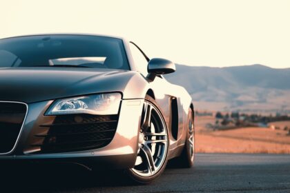 A silver sports car parked on a road with mountains in the distance
