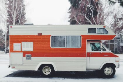 orange and white class-a motorhome surrounded by snow