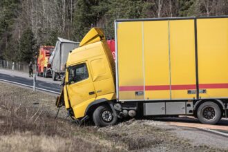 A yellow semi-truck is in a roadside accident