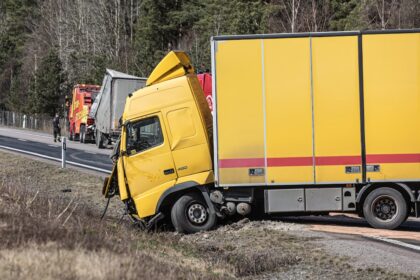 A yellow semi-truck is in a roadside accident