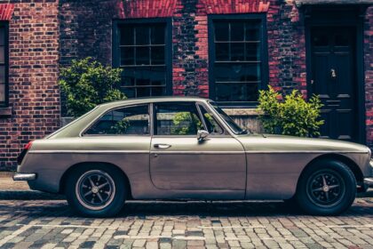 an old car is parked in front of a brick building