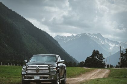 A truck drives on a dirt road with mountain views