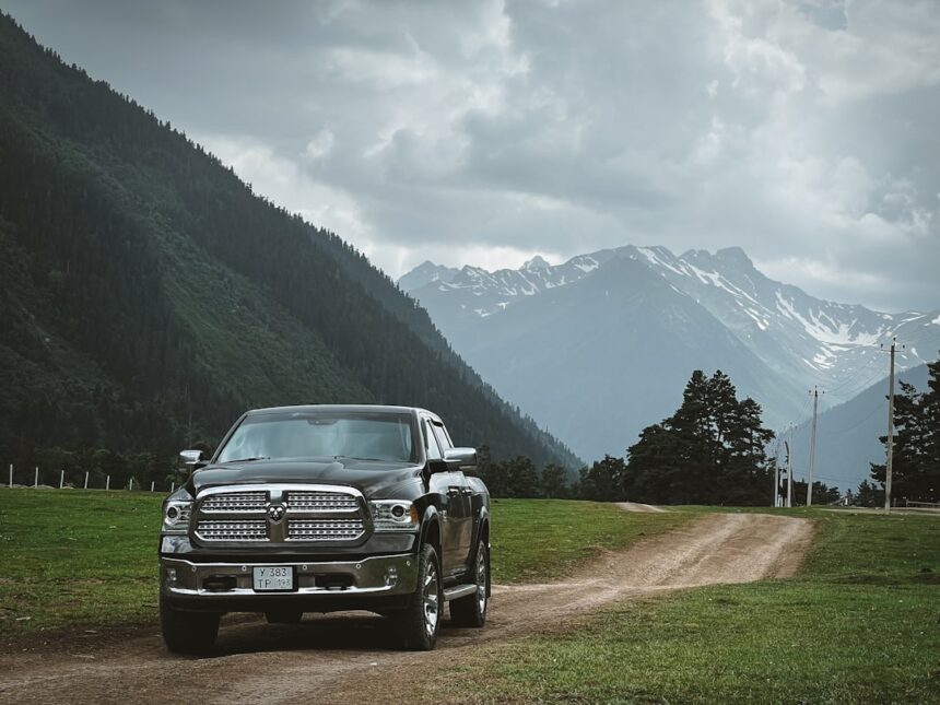 A truck drives on a dirt road with mountain views