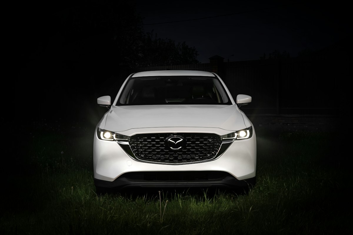 White Mazda CX-5 photographed head-on at night with headlights on
