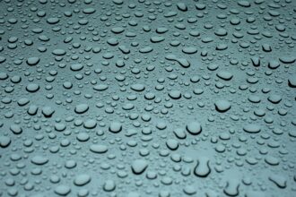 Water droplets beading and drying on a teal car panel