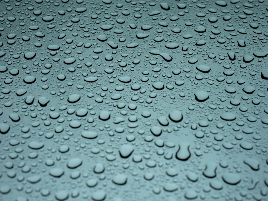 Water droplets beading and drying on a teal car panel